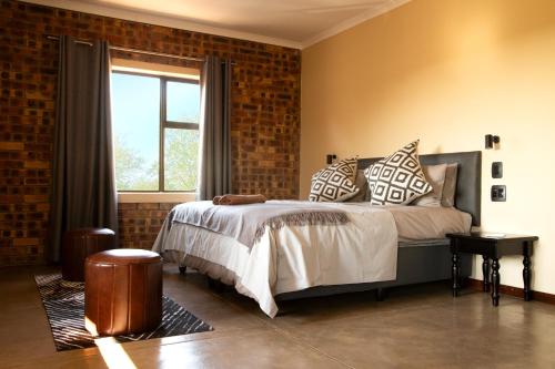 ein Schlafzimmer mit einem Bett mit Kissen und einem Fenster in der Unterkunft Melamar Estate in Marloth Park