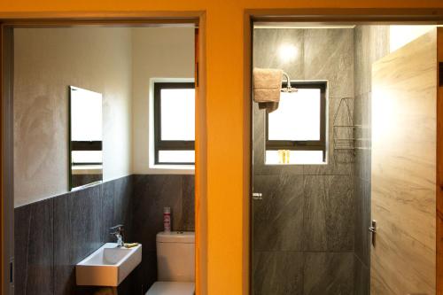 ein Badezimmer mit einem Waschbecken, einem WC und einem Spiegel in der Unterkunft Melamar Estate in Marloth Park