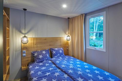 a bedroom with a blue bed and a window at Siblu De Lente van Drenthe in Gasselte