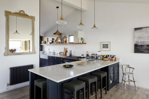 a kitchen with a large island with bar stools at Stunning architect designed beachfront property in Selsey