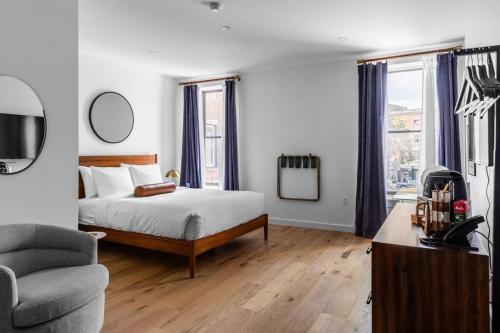 a bedroom with a bed and a chair and a television at Historic Hotel, Heart of Bangor, Fiber Wi-Fi, Roku TV, Room # 206 in Bangor