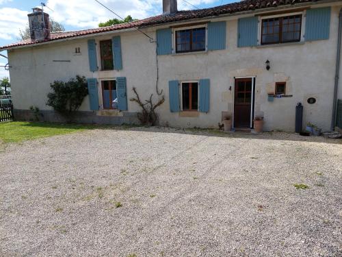 a white house with blue windows and a driveway at B&B Franglaise in Romagne