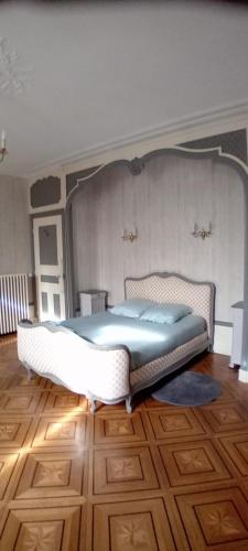 a large bed in a room with a wooden floor at Manoir de la Saône in Seurre