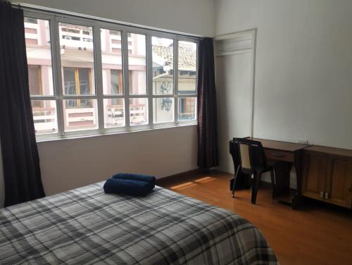 a bedroom with a bed and a desk and windows at DEPARTAMENTO SANTIAGO_REYES in Cuenca
