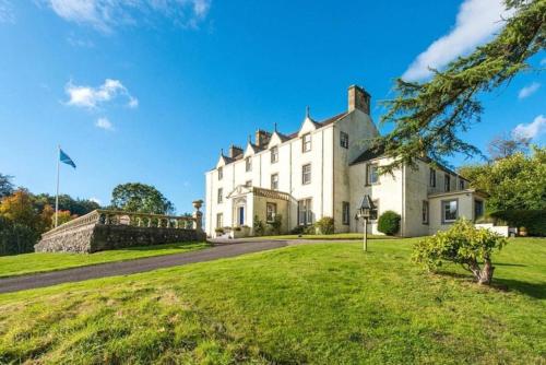 an exterior view of a large white house with a green lawn at Carphin House near St Andrews - Sleeps 18 in Fife