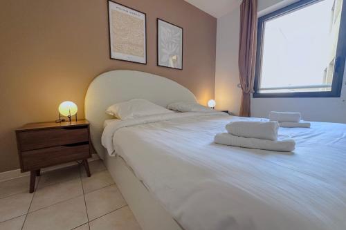 Un dormitorio con una gran cama blanca y una ventana en St Roch 2 - Appart 300 m de la Gare, clim, terrasse, garage, en Antibes
