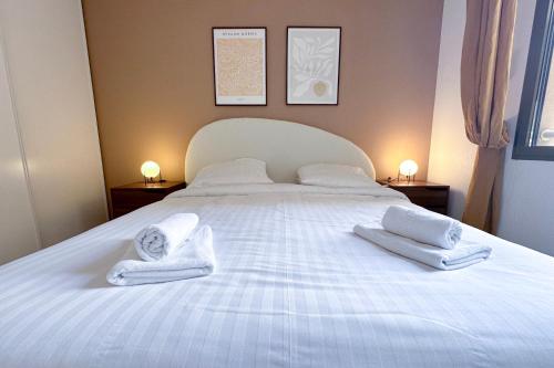 Una cama blanca con toallas encima. en St Roch 2 - Appart 300 m de la Gare, clim, terrasse, garage, en Antibes