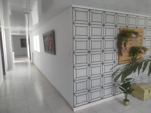 a hallway with a white tile wall with a plant at Edificio Tony - Alojamiento Aparta-Hotel in Barrancabermeja