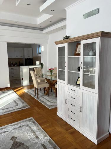 a kitchen and dining room with a large white cabinet at Airport SKY apartments LUX II in Belgrade