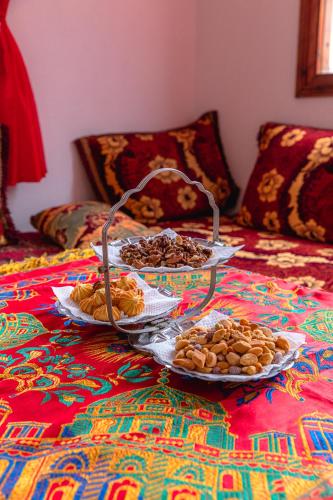 a table with three plates of food on a bed at Amazigh Family Riad in Imlil