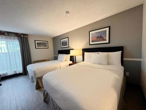 a hotel room with two beds and a window at Divya Sutra Plaza and Conference Centre Calgary Airport in Calgary
