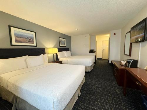 a hotel room with two beds and a television at Divya Sutra Plaza and Conference Centre Calgary Airport in Calgary
