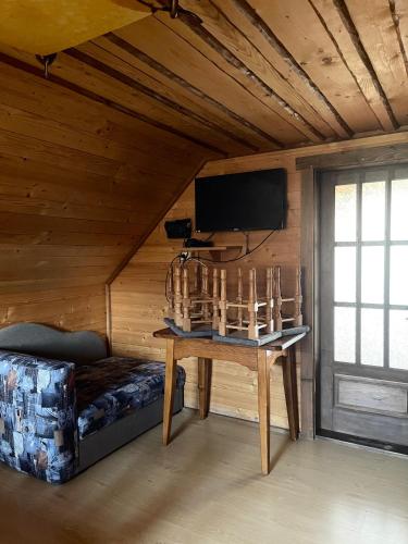 a room with a table and a tv on a wall at Khatky Na Penkakh in Vorokhta