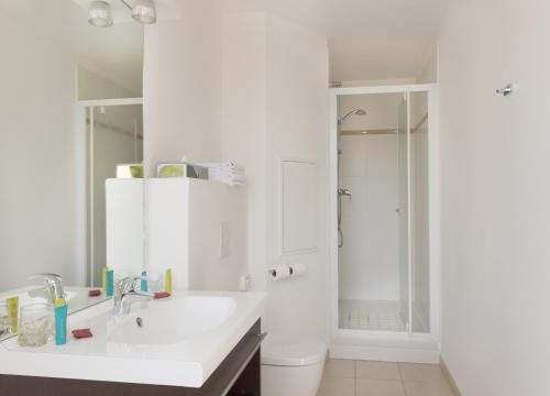 La salle de bains blanche est pourvue d'un lavabo et d'une douche. dans l'établissement Plessis Parc Hôtel, au Plessis-Robinson