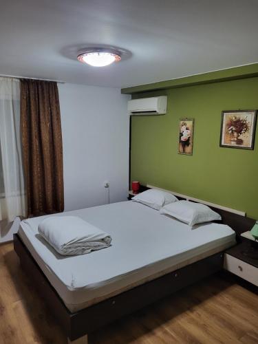 a bedroom with a white bed with a green wall at Solar in Plovdiv