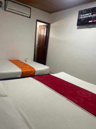 two beds in a room with a sign on the wall at Hotel Descanso Inn Villavicencio in Villavicencio