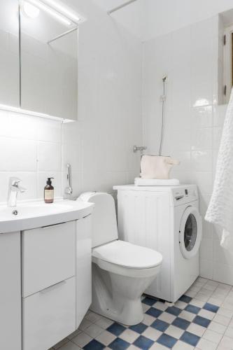 a white bathroom with a toilet and a washing machine at Charming Flat in Design District in Helsinki