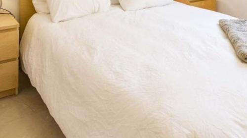 un letto bianco con lenzuola e cuscini bianchi di Casa Badia de Palma a Calvià