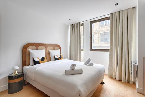 une chambre avec un grand lit blanc avec une grande fenêtre dans l'établissement Sentier Historical Center Luxury & Design Apartment 2BR, à Paris