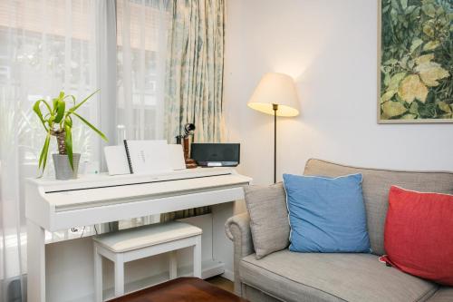 a living room with a white piano and a couch at Beautiful 1 Bedroom in The Heart of Bethnal Green in London