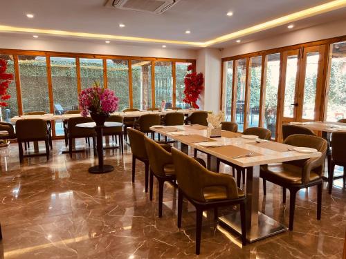a dining room with tables and chairs and windows at Hotel Mayto in Thimphu