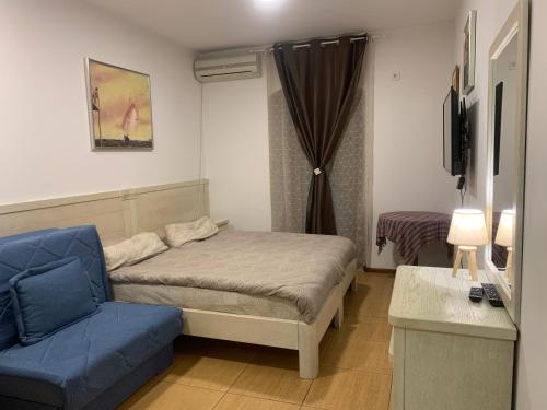 ein kleines Schlafzimmer mit einem Bett und einem blauen Sofa in der Unterkunft Apartments Amber House in Topla