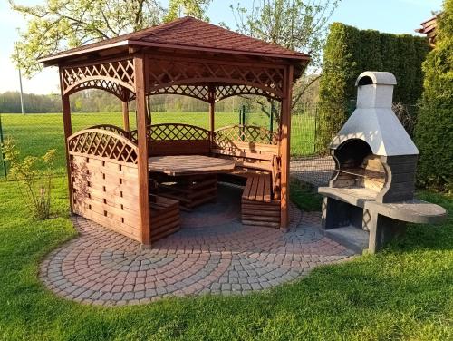 a wooden gazebo with a fireplace in a yard at Domek nad stawem z balią i sauną in Sulęczyno