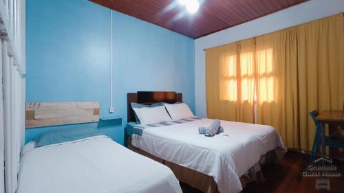 Duas camas num quarto com paredes azuis em Gramado Guest House em Gramado
