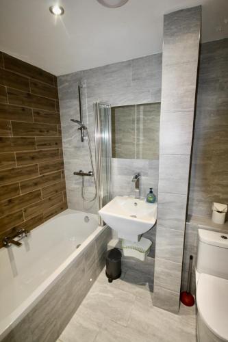 a bathroom with a sink and a tub and a toilet at Bournemouth Hot Tub & Sauna Holiday Let in Bournemouth