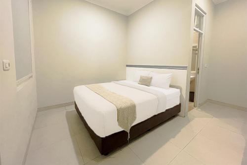 Mooi Inn City Center Surabaya في سورابايا: غرفة نوم بسرير وملاءات بيضاء ونافذة