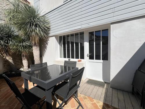 eine Terrasse mit einem schwarzen Tisch und Stühlen neben einer Tür in der Unterkunft Maison de village L'A N N E X E proche du port in Saint-Martin-de-Ré