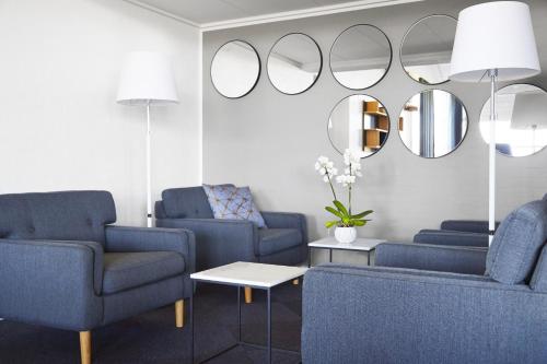 a living room with two blue chairs and mirrors at HORISONT Hotel & Konference in Aarhus
