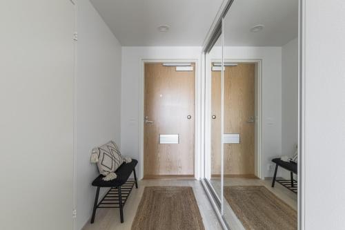 a hallway with glass doors and chairs in a room at Modern studio by Finnoo metro in Espoo