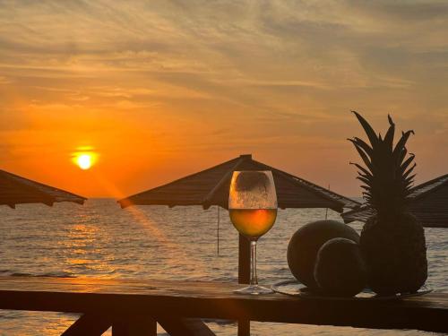 um copo de vinho numa mesa na praia com o pôr do sol em APARTASUITE A UN PASO DEL MAR em Tolú