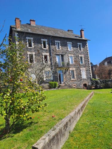 un vieux bâtiment en briques avec un arbre devant lui dans l'établissement Les Chambres du Cheval Blanc, à Allassac