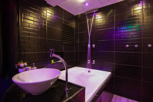 a bathroom with a sink and a tub with purple lights at Adrenalina Motel Itaquera - Arena Corinthians in Sao Paulo