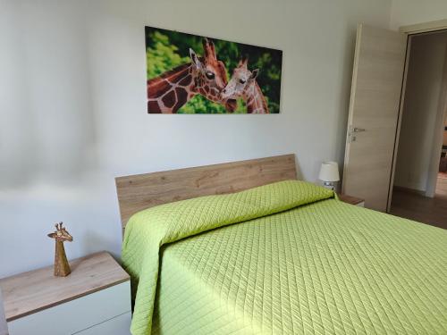 a bedroom with a green bed and a picture of giraffes at Appartamento donatello in Imola