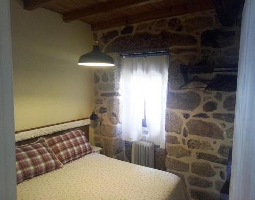 1 dormitorio con pared de piedra y ventana en C Vilamide, en Parada de Achas