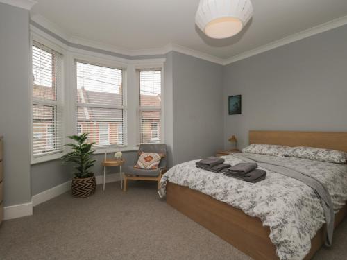 a bedroom with a bed and a chair and windows at 6 Sydney Road in Ramsgate