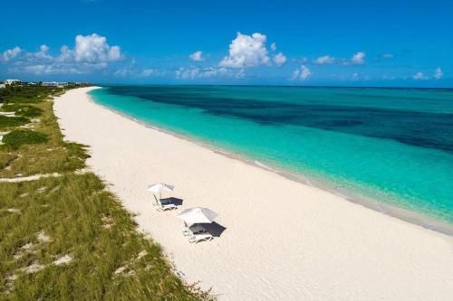two white umbrellas on a beach with the ocean at Casa Grande - Grace Bay Beach in The Bight Settlements