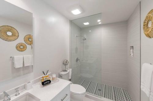 a white bathroom with a shower and a toilet at Casa Grande - Grace Bay Beach in The Bight Settlements