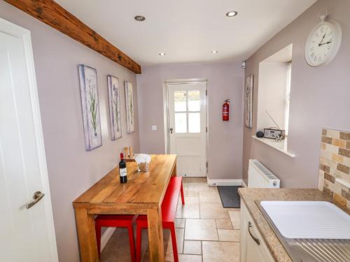 uma cozinha com uma mesa de madeira e cadeiras vermelhas em Erin Cottage formerly Chloe's Cottage em Keighley