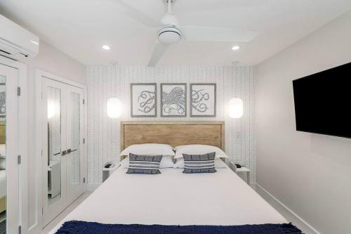 a white bedroom with a bed and a flat screen tv at Casa Grande - Grace Bay Beach in The Bight Settlements
