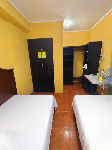 two beds in a room with yellow walls and a door at Habitación 1, 2 Camas Individuales in Matamoros