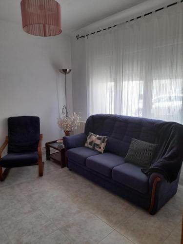 uma sala de estar com um sofá azul e uma cadeira em Ca l'Avi Ramon em Sant Hilari Sacalm