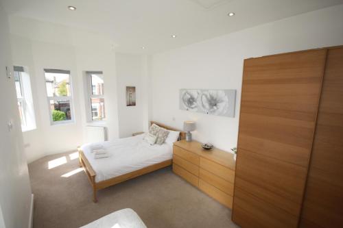 Schlafzimmer mit einem Bett und einem Holzschrank in der Unterkunft Holiday Home Hot Tub & Sauna in Bournemouth
