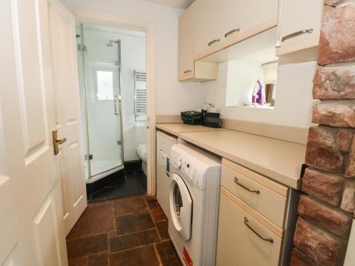 a small kitchen with a washer and dryer at Saddleback Barn in Penrith