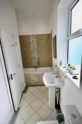 a white bathroom with a sink and a tub at Holiday Home Hot Tub & Sauna in Bournemouth