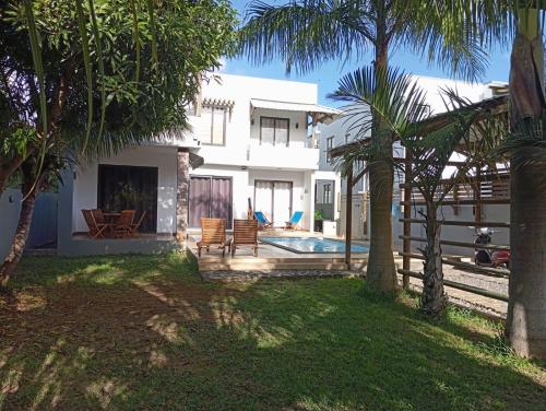 Casa blanca con piscina y palmeras en Villa Coco en Trou aux Biches