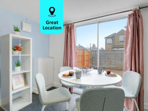 een eetkamer met een witte tafel en stoelen en een raam bij Chic 1BR House in Hounslow - 12 mins From HEATHROW AIRPORT in Feltham